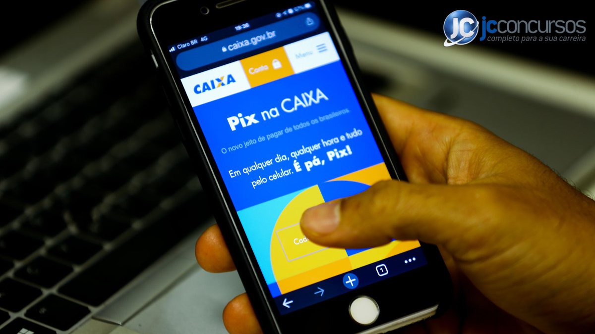 Homem segura o celular aberto com o site da Caixa
